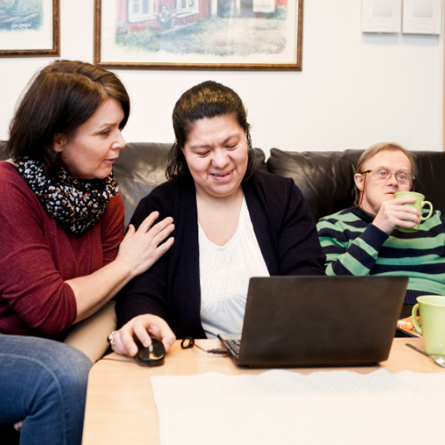 Community health worker helping a woman and man with down syndrome.