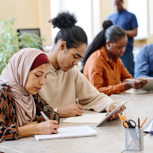 A group of diverse professionals writing at a table during training.