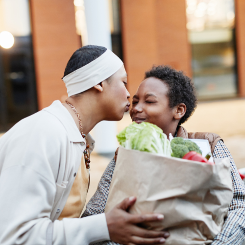 Mom kissing son on the cheek as he helps with groceries.