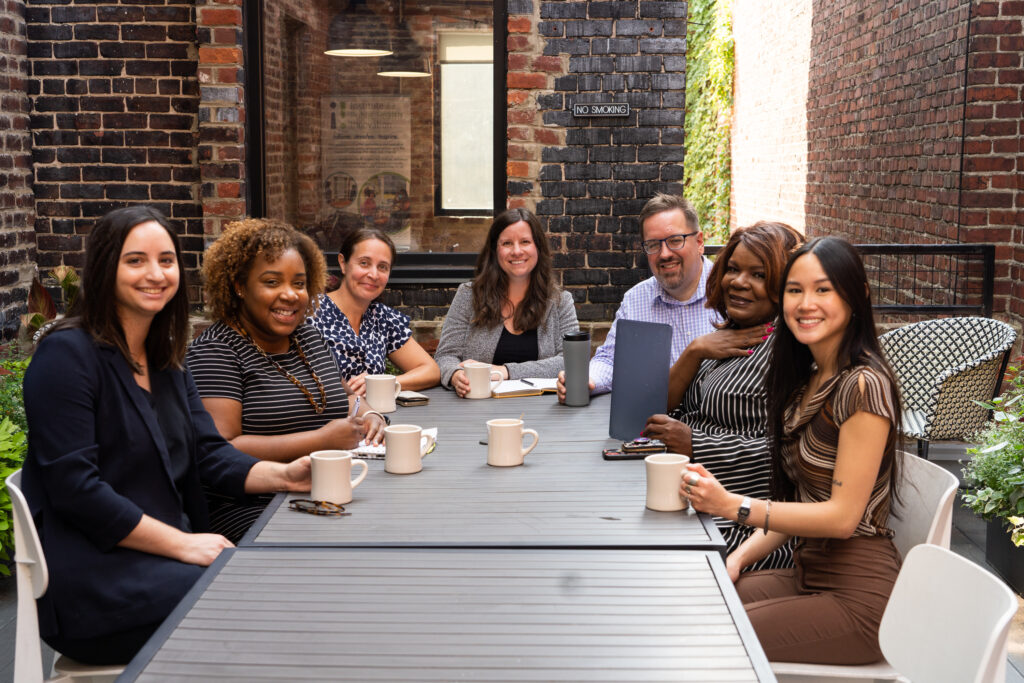 IPHI team members gathered around a table enjoying coffee together.