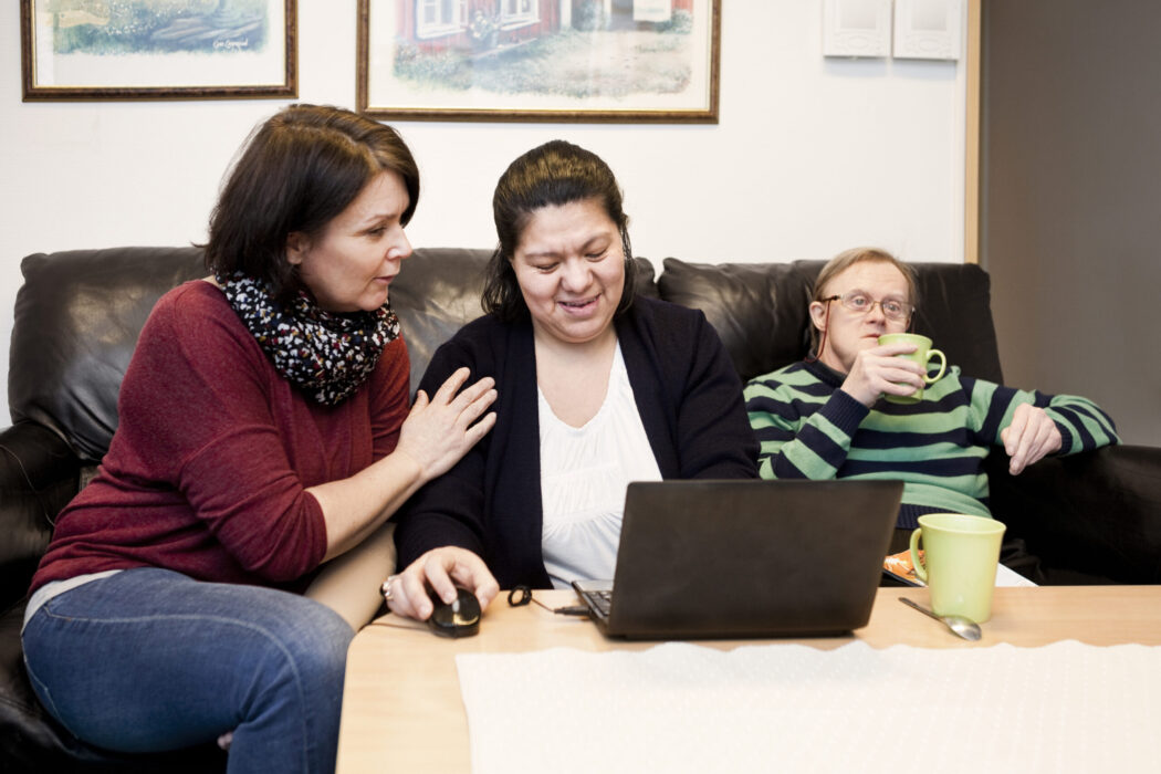 Community health worker helping a woman and man with down syndrome.