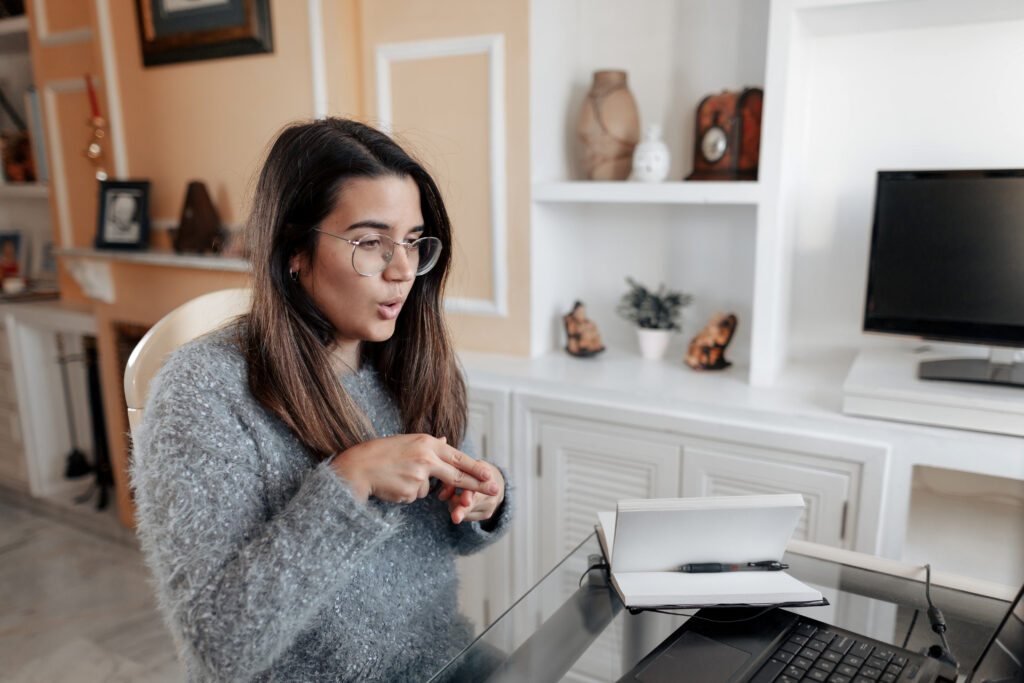 A deaf woman is having a non-verbal conversation using sign language in an online video call.